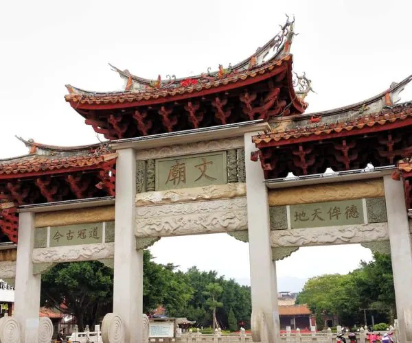 Quanzhou Prefectural Confucian Temple,Quanzhou,Chinatravel Large ornate Chinese temple gate with curved red-tiled roofs, dragon ornaments, and stone carvings.