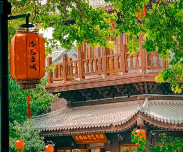 Luoyi Ancient City,Luoyang,Chinatravel Traditional Chinese pavilion with orange lanterns in a lush garden courtyard.