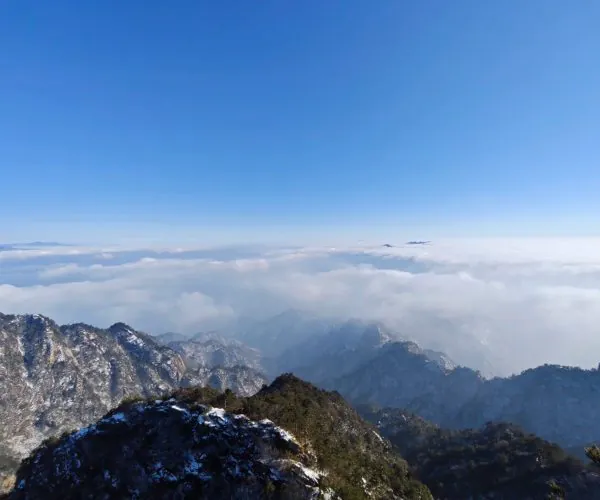 Baiyun Mountain & Scenic Area,Luoyang,Chinatravel Snow-dusted rocky mountain ridge rises above a sea of clouds under a clear blue sky.
