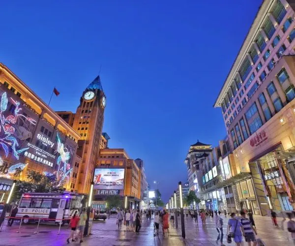 Wuangfujing, Beijing, chinatravel, Pedestrian street at dusk with illuminated storefronts and a tall clock tower against a deep blue sky.)