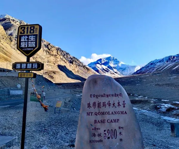 Mount Everest Base Camp,Lhasa,Chinatravel Stone marker at Mt. Qomolangma Base Camp with altitude 6200m and surrounding rocky trail under a clear blue sky.