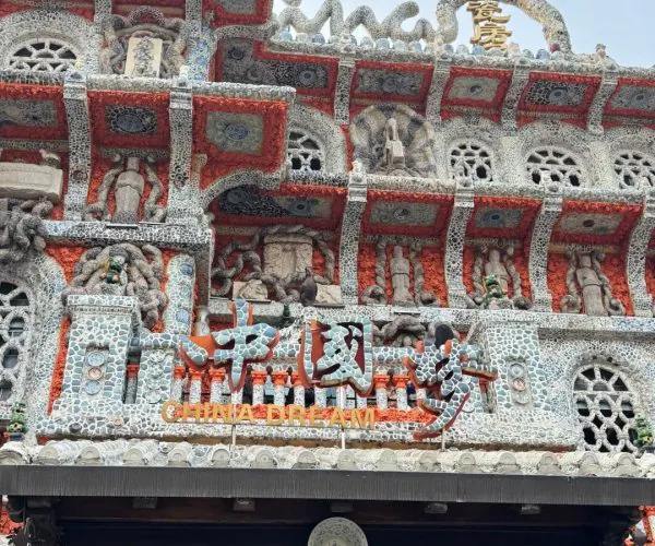 Ornate mosaic storefront with red and white stone, intricate statues, and the sign 'China Dream' in gold lettering