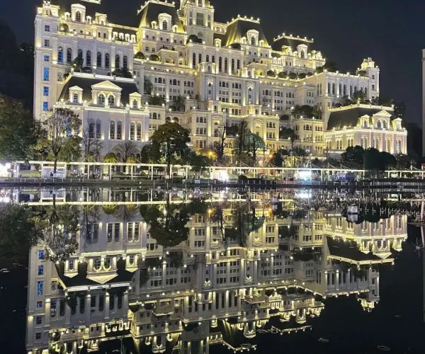 White House,Guiyang,Chinatrip Grand white, castle-like hotel lit at night, its ornate architecture reflected in a calm water body.