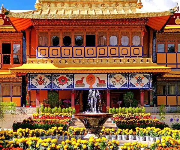 Norbulingka Park,Lhasa,Chinatravel Ornate golden temple facade with blue sky, surrounded by a colorful flower garden and a central fountain.