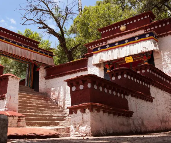 Sera Monastery,Lhasa,Chinatravel Entrance to a Tibetan-style temple with red walls, white decorative dots, and a stairway leading to a decorated doorway outdoors.