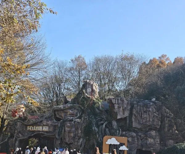 huashanmiku Scenic Area,Huangshan,Chinatravel Rocky theme park entrance with carved Chinese characters and tree-root design, people lined up beneath a clear blue sky