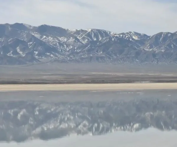 Chaka Salt Lake,Xining,Chinatrip Snow-capped mountain range reflected in a calm body of water under a blue sky.