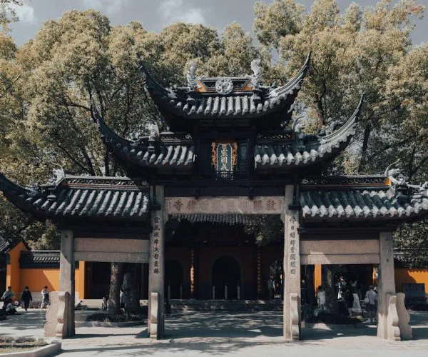 Xiyuan Temple,Suzhou,Chinatravel Traditional Chinese temple gate with curved tiled roofs and stone pillars, surrounded by trees and visitors