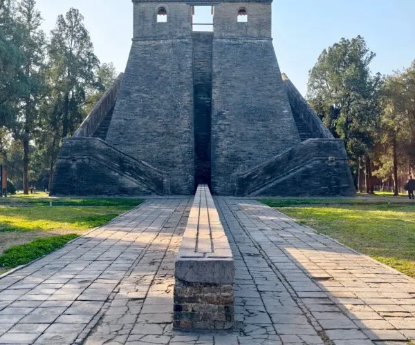 Observatory,Shaolin & Songshan Area,Chinatrip Front view of a historic stone monument with twin staircases and a central opening, surrounded by trees in a park setting.