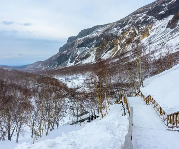 Changbai Mountain,Baishan,Chinatrip Snowy mountain trail with a wooden railing winding down toward a valley.