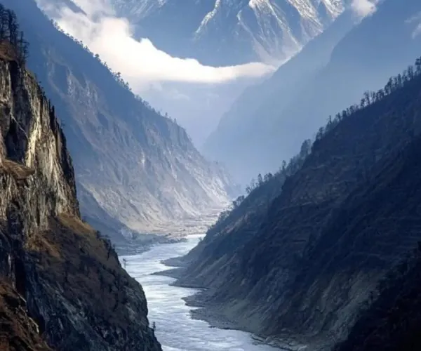 Yarlung Tsangpo Grand Canyon,Nyingchi,China tour Snow-capped mountains rise above a winding river valley with steep rocky slopes and misty air