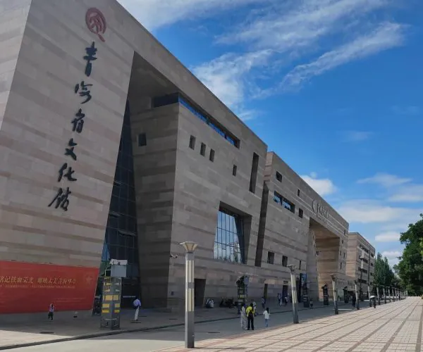 Qinghai Provincial Museum,Xining,Chinatrip Modern cultural center with tall stone walls, large Chinese characters on the left, and a wide tiled plaza under a blue sky.