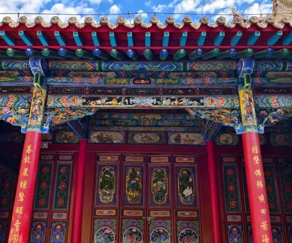 Gao Temple,Zhongwei,China tour Colorful Chinese temple facade with red pillars, ornate painted beams, and decorative doors under a bright blue sky.
