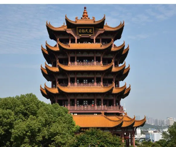 Yellow Crane Tower,Wuhan,Chinatravel Five-story Chinese pagoda with orange tiled roofs against a blue sky, surrounded by greenery.