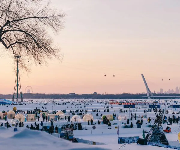 Heilongjiang Weather,Heilongjiang,Chinatravel Wide snowy park crowded with people, cable cars gliding across the sky, and a distant city skyline at sunsetlightened by pastel skies.