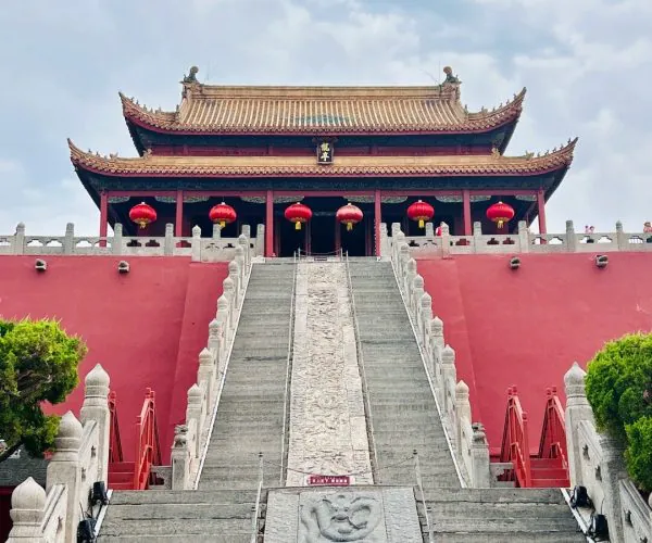 Dragon Pavilion Park,Kaifeng,Chinatravel Temple with red walls and ornate curved roofs, stairs leading to a pagoda-style hall adorned with red lanterns.
